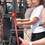 Pracownicy Polychem Systems symbolicznie otwierają nowy budynek firmy, nacinając nożyczkami czerwoną wstęgę.