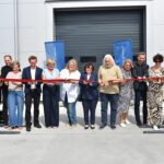 Pracownicy Polychem Systems wspólnie przecinają czerwoną wstęgę otwierając nowy budynek biurowo-magazynowy.