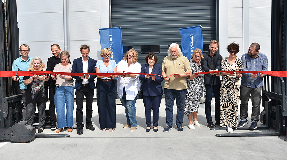 Zdjęcie grupy pracowników Polychem Systems przecina symboliczną czerwoną wstęgę